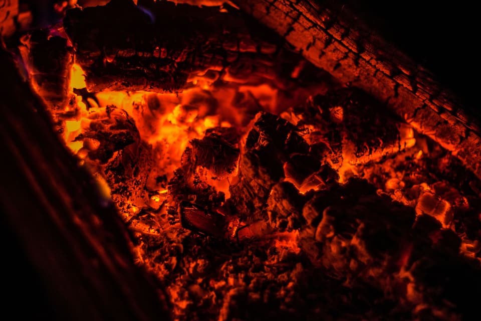 Glowing embers and charred oak in a wood fire