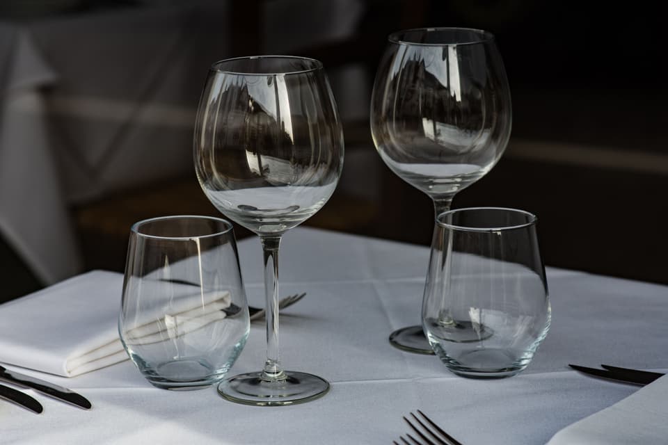 Wine glasses, folded napkins and cutlery on a white tablecloth