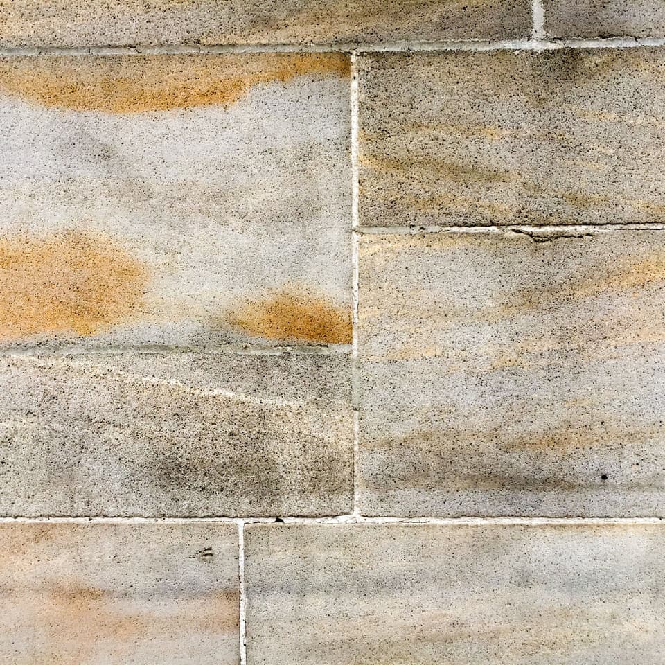 A close view of pale sandstone slabs, rust-coloured bands running through them.